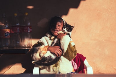 微笑的女孩抱着倚在墙上的猫